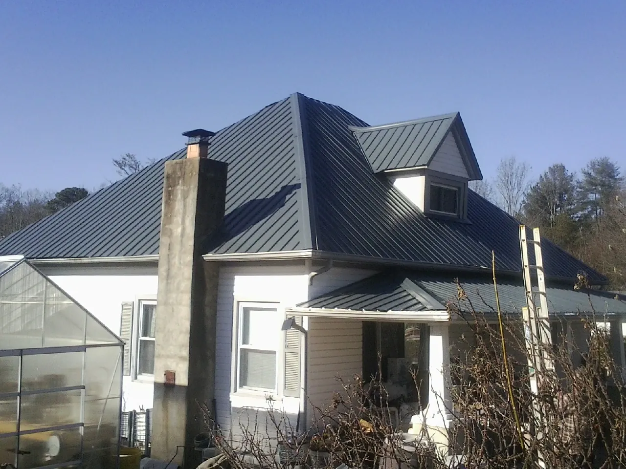 Dark blue standing seam metal roof on a white farmhouse with dormer — Slate & Tile Roof Repair by Roofing Brothers in Pleasureville