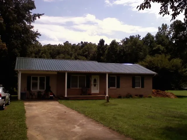 Dark green metal roof on a brick ranch with a covered porch in Pleasureville
