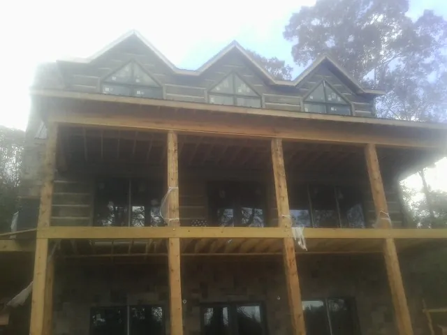 Dormers and porch framing on a large log home under construction — Roof Coating work by our crew in Pleasureville
