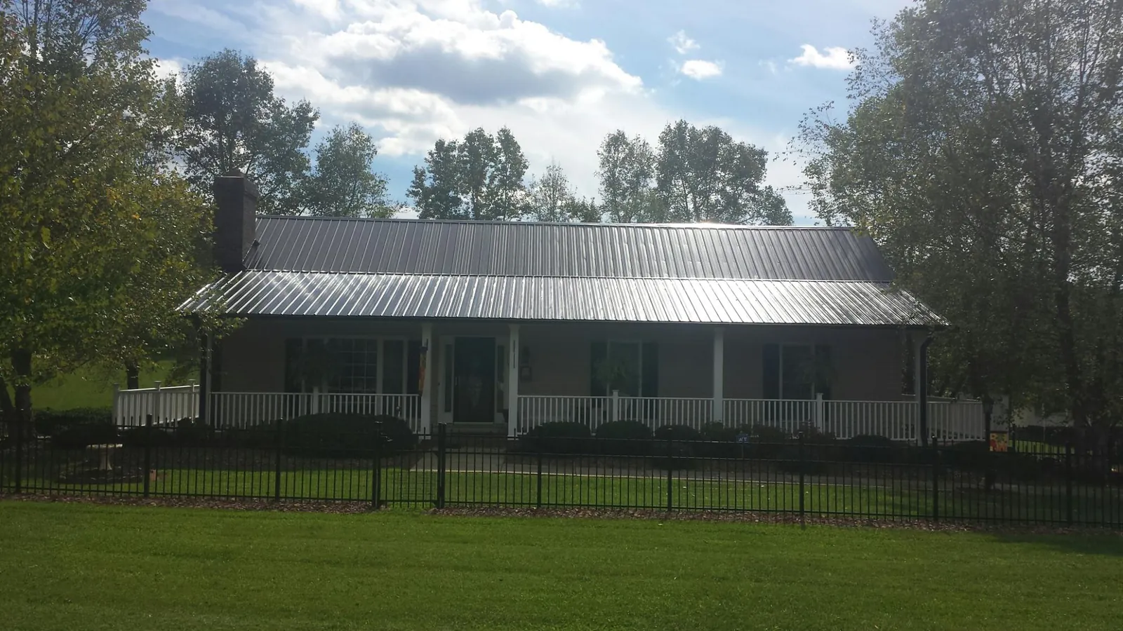 Gray metal roof on a brick ranch with a full width front porch — Gutter Guard Installation work by our crew in Pleasureville