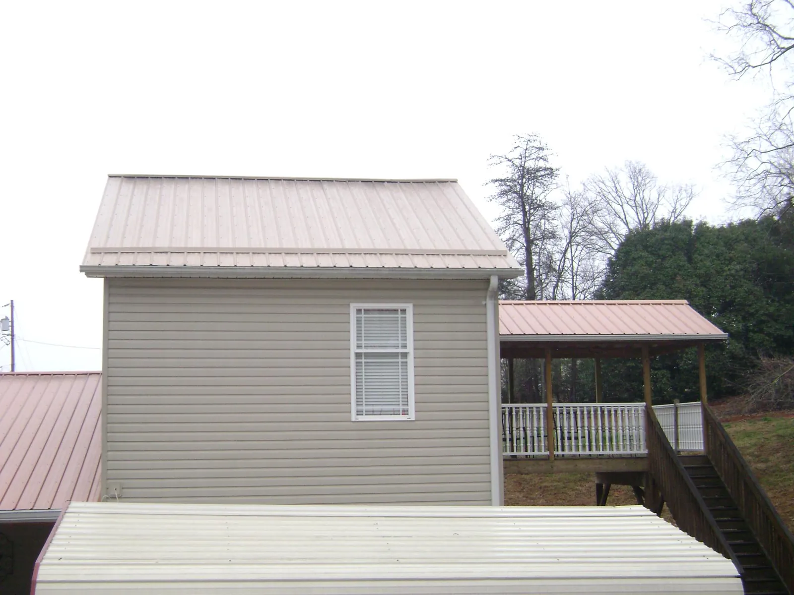 Tan metal roofs on a two story addition and attached porch, from a Roof Replacement job in Pleasureville