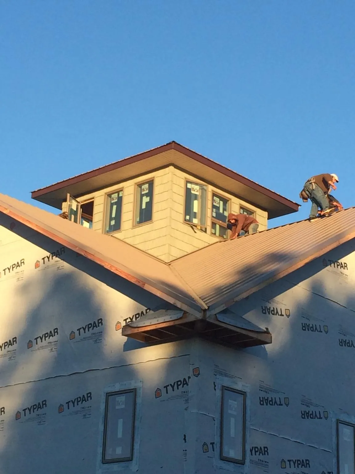 Roofers working around a rooftop cupola on a new metal roof at sunset — Roof Waterproofing in Pleasureville by Roofing Brothers